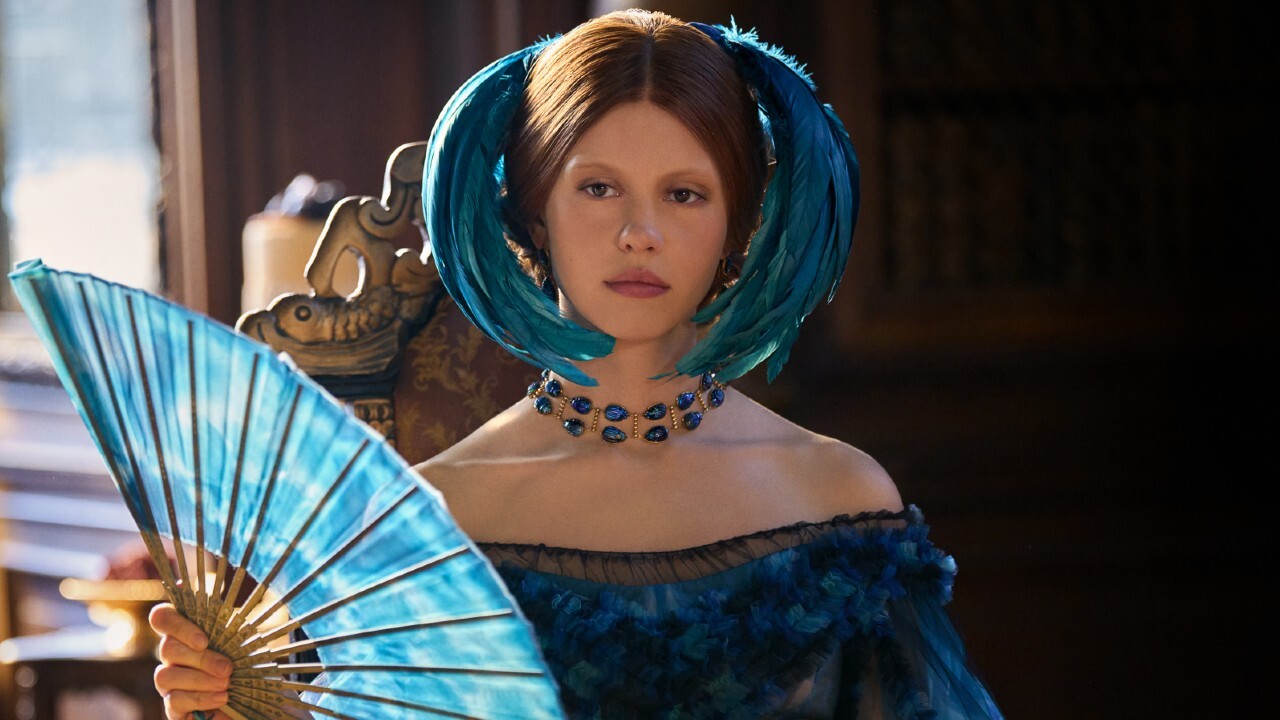 A somber Mia Goth fanning herself in Guillermo Del Toro's Frankenstein.
