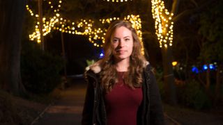 A woman smiling with fairy lights behind