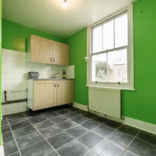 before shot of a rundown green kitchen with black floor tiles and green walls