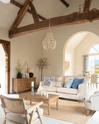 California cool home with tall ceiling and wooden beams. Cream upholstery mixed with rattan, raw wood, jute and beading