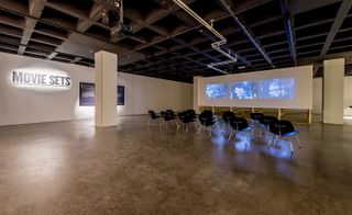 Three projection screens showcase the photographs