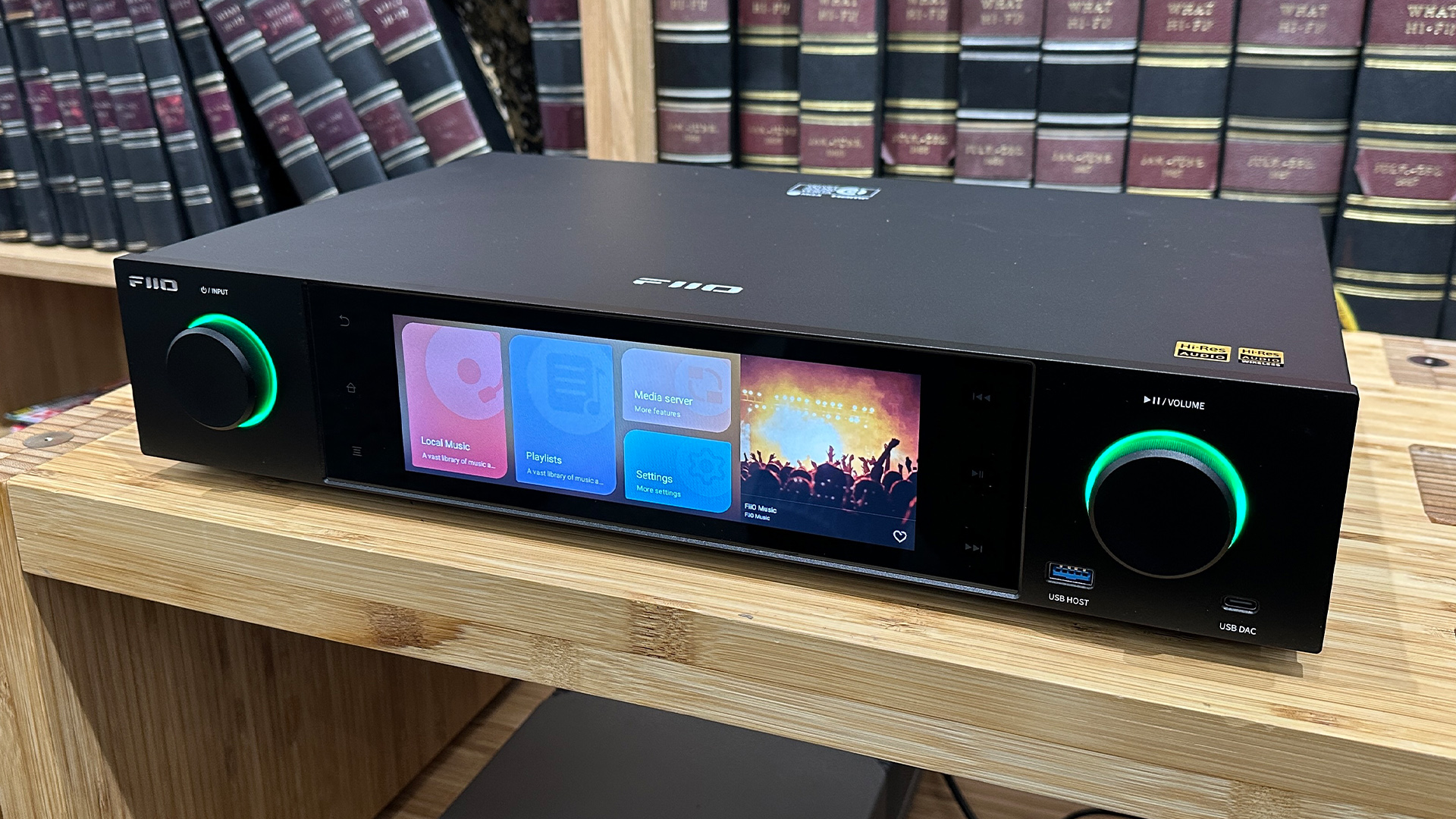 FiiO S15 music streamer on wooden hi-fi rack in front of bookcase