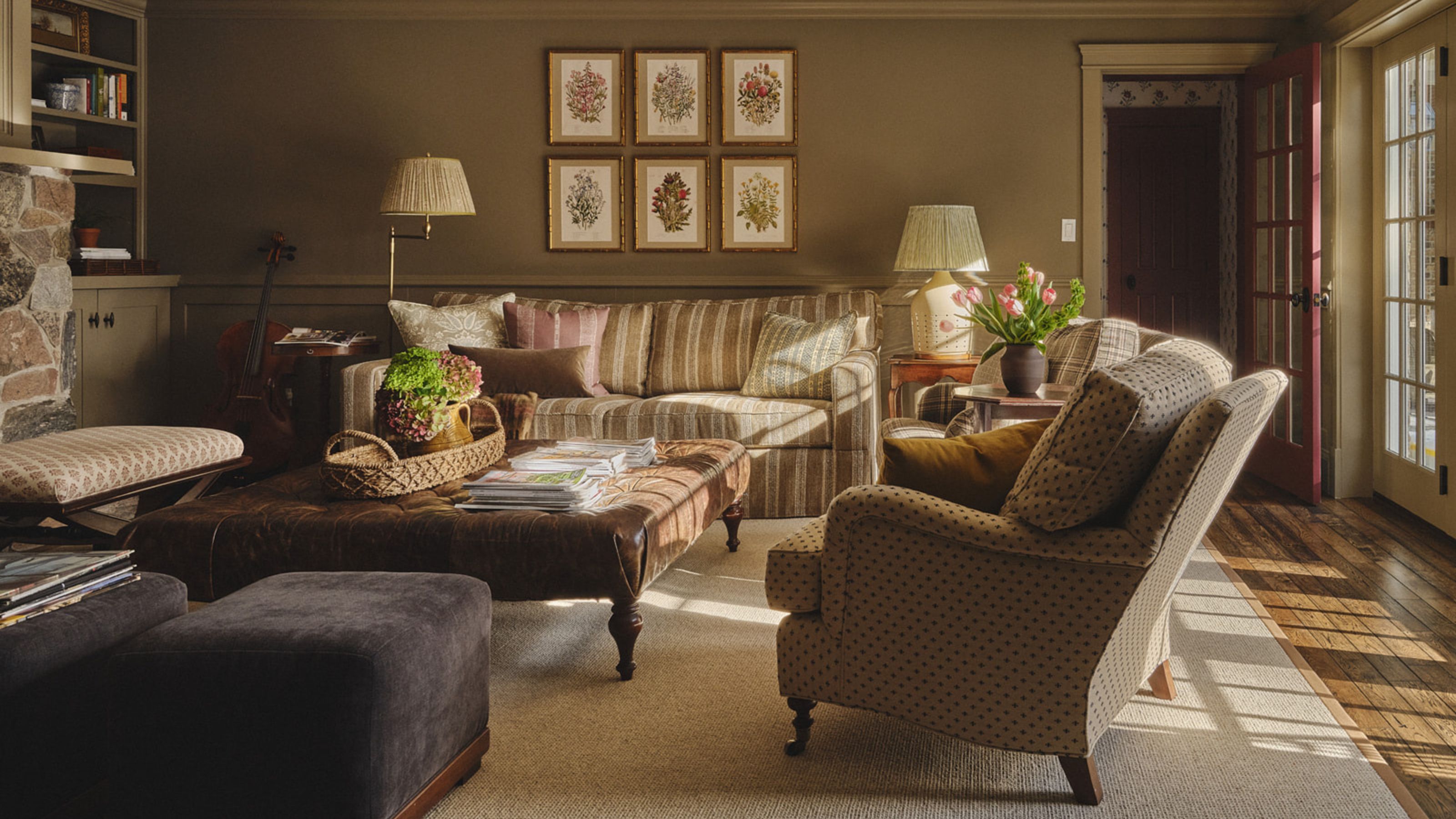 an earthy soft brown color drenched den snug room with striped couch, patterned armchairs, stone fireplace and alcove book shelves