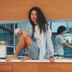 Woman sat on top of tabletop in denim shorts