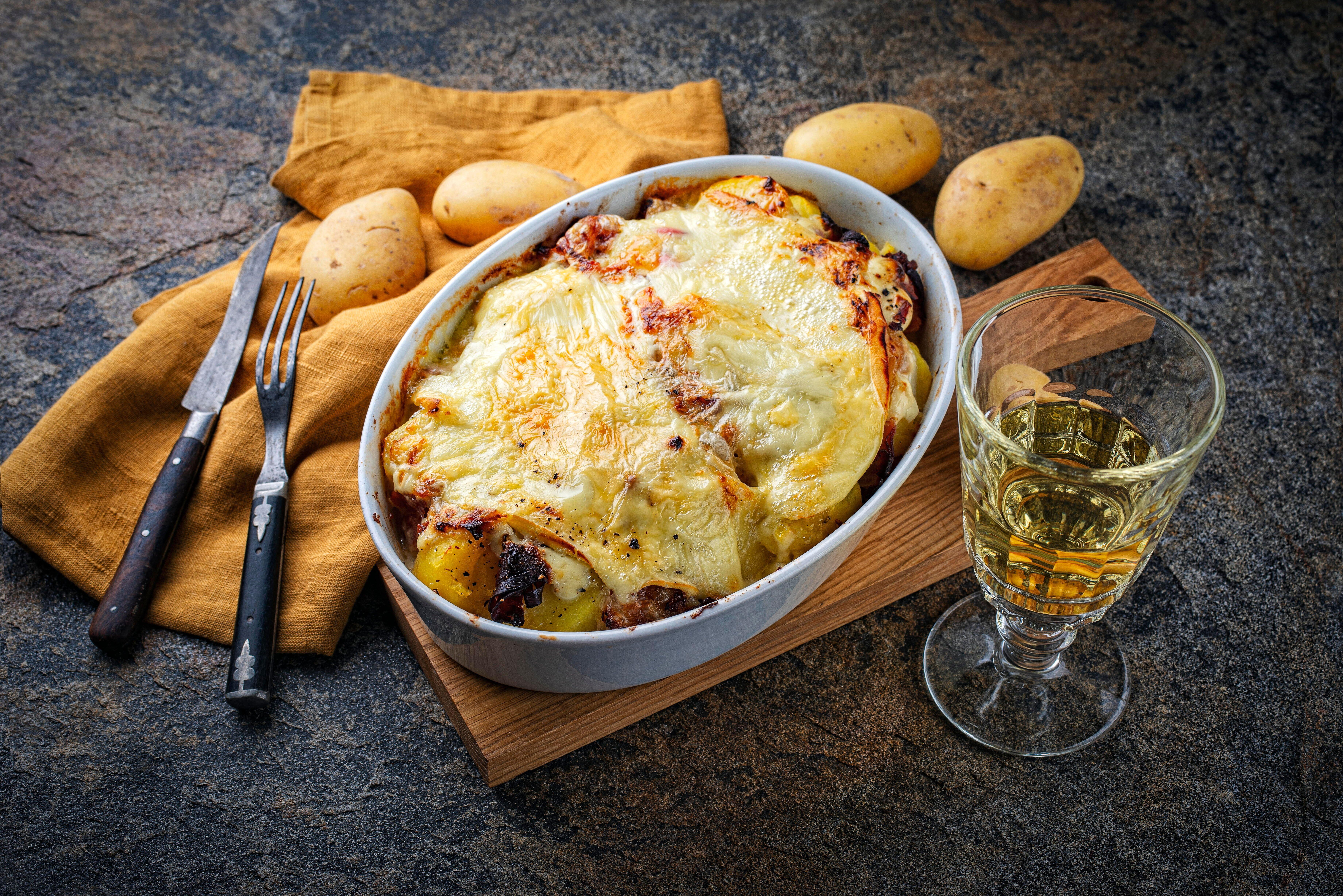 artisan homemade oven baked Tartiflette wih potato and reblochon cheese in casserole dish