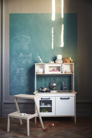 Blue chalkboard wallpaper and a play kitchen illustrating playroom design ideas.