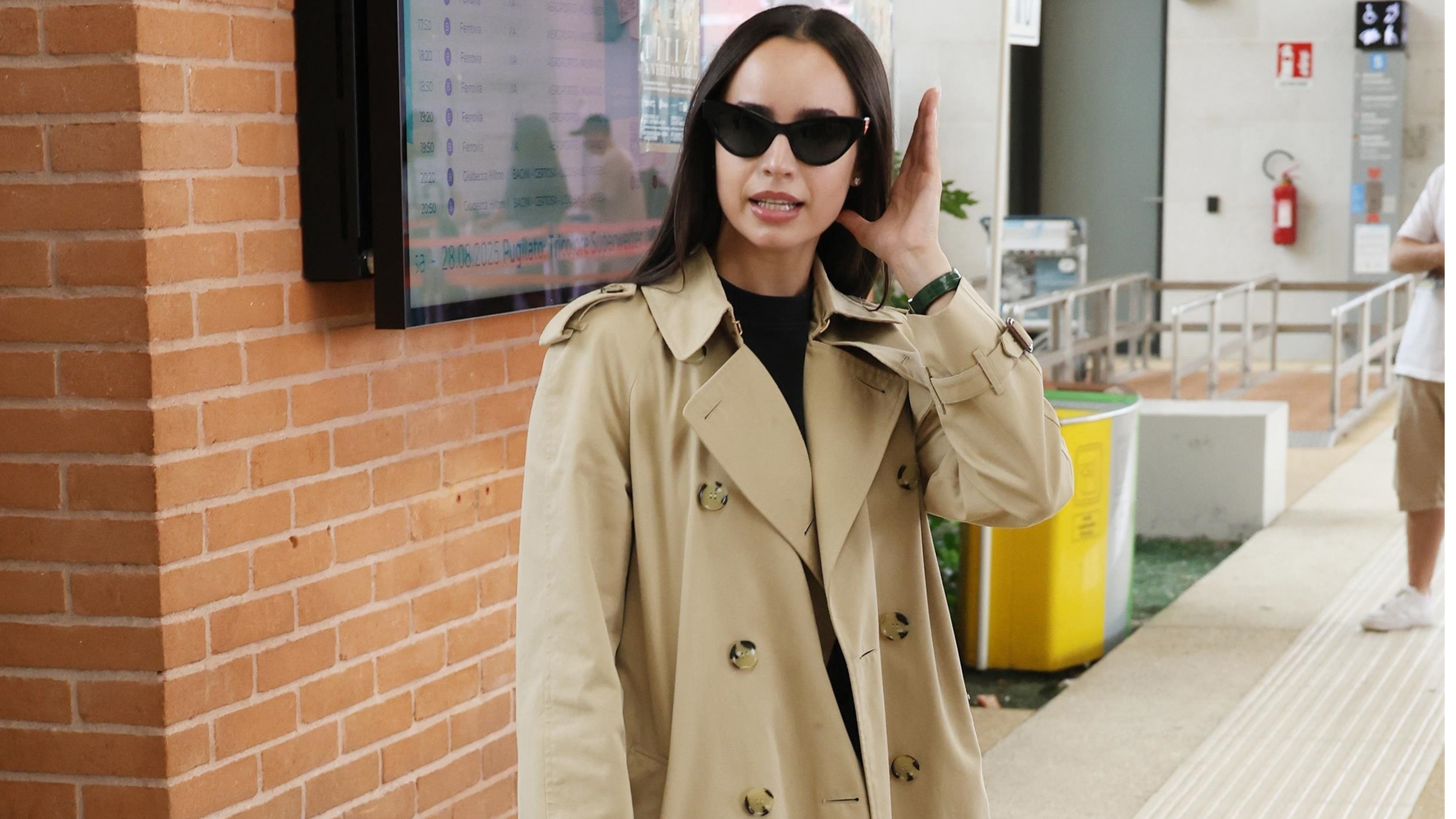 Sofia wears a trench coat, chanel bag, black trousers, and adidas samba sneakers.