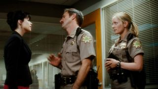 Neve Campbell being stopped by David Arquette, while Marley Shelton stands behind him in Scream 4.