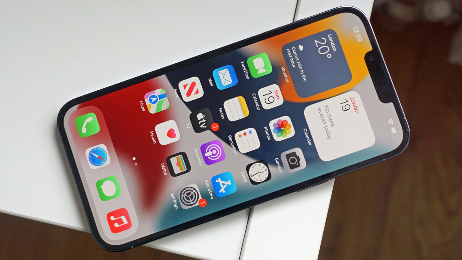 iPhone 13 Pro Max lies on a table face up and displays the home screen