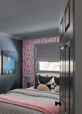 a bedroom with pink wallpaper accent wall