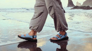 Person walking along beach wearing Birkenstock Mogami Terra sandals