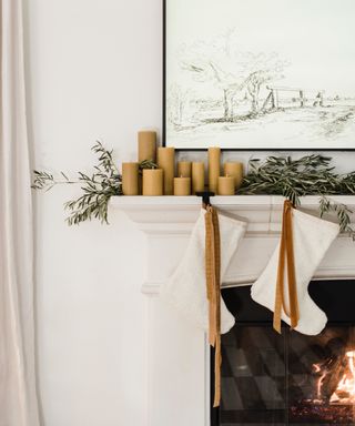 White mantelpiece with stockings , natural garland and ribbon