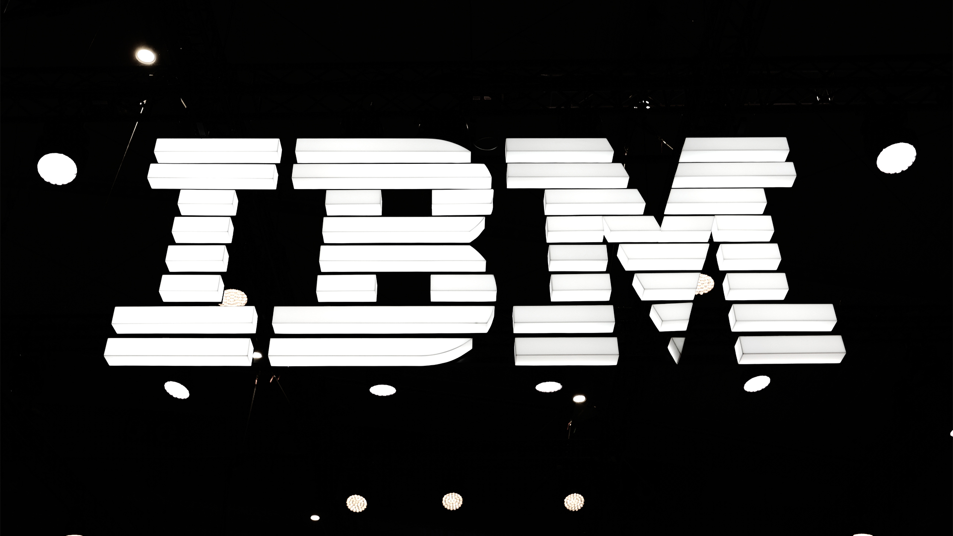 IBM logo illuminated in white against a black background at the company's exhibitor stall at Mobile World Congress 2025. 