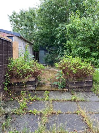 Outdoor kitchen: a before shot showing uneven grey paving and overgrown weeds