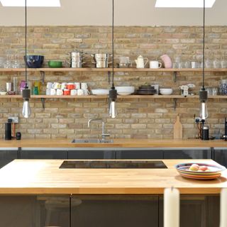 Brick wall kitchen with wooden and grey counters and island units