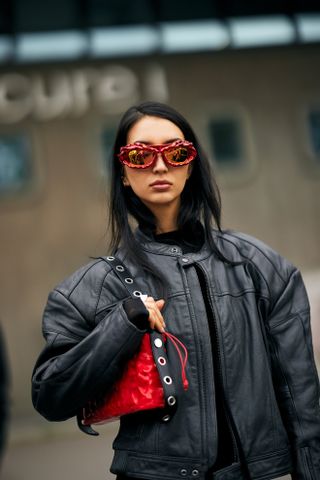 A woman at Paris Fashion Week Spring 2025 with her hair tucked into a black sweater and black leather jacket