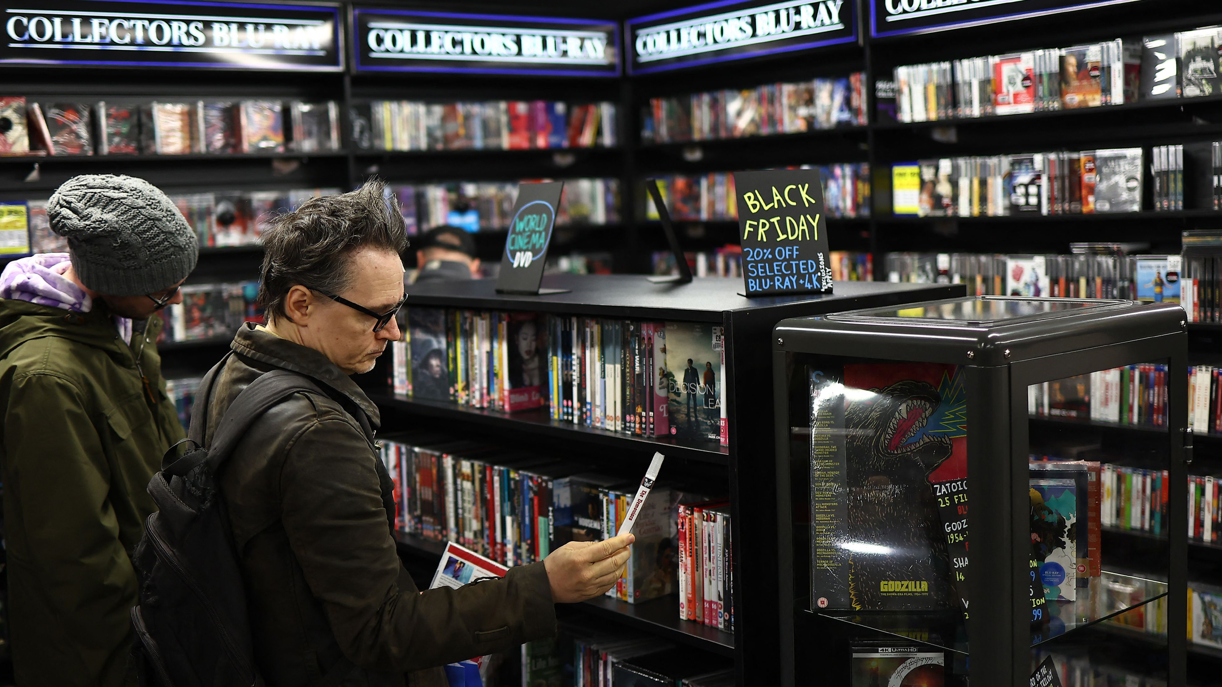 Man browsing in DVD shop – Black Friday sign on the cabinet