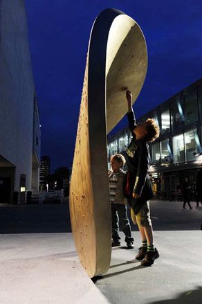 Two kids placing coins on the large magnetic installation. Photographed at dusk