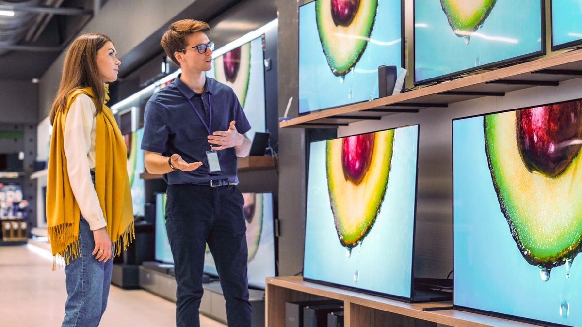 woman shopping for TV with retail worker giving advice 