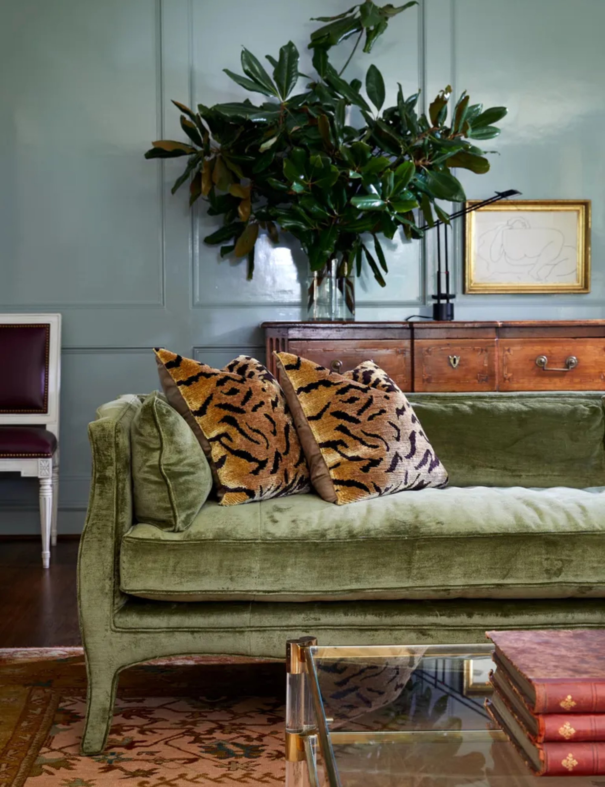 Green velvet sofa with tiger pattern cushions and blue walls