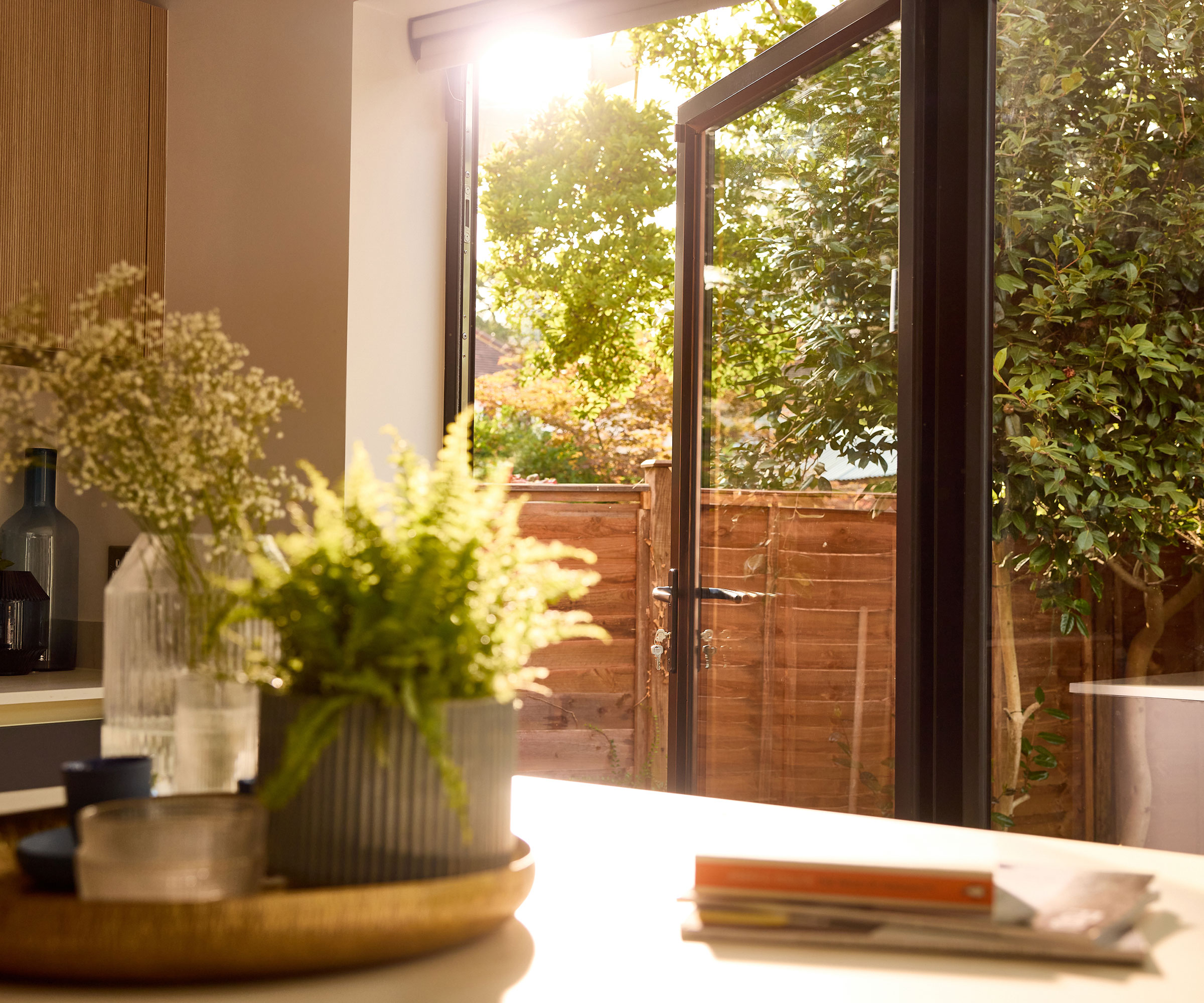 end door of a set of bifolding doors leading out to a garden, with a kitchen worktop in the foreground