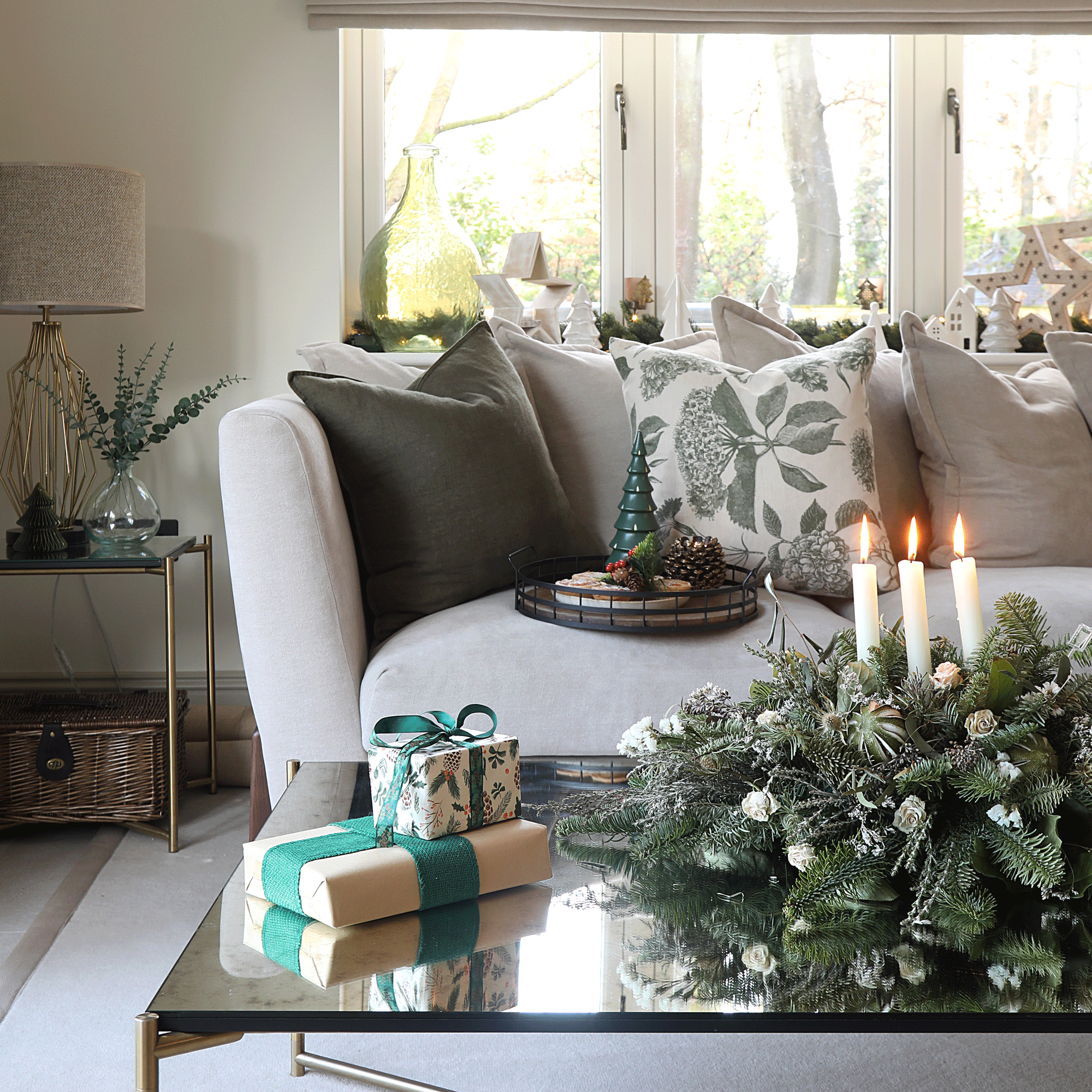 a festive living room with Christmas decorations and a centrepiece covered in foliage with three lit candles