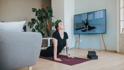 Woman practising yoga in front of TV