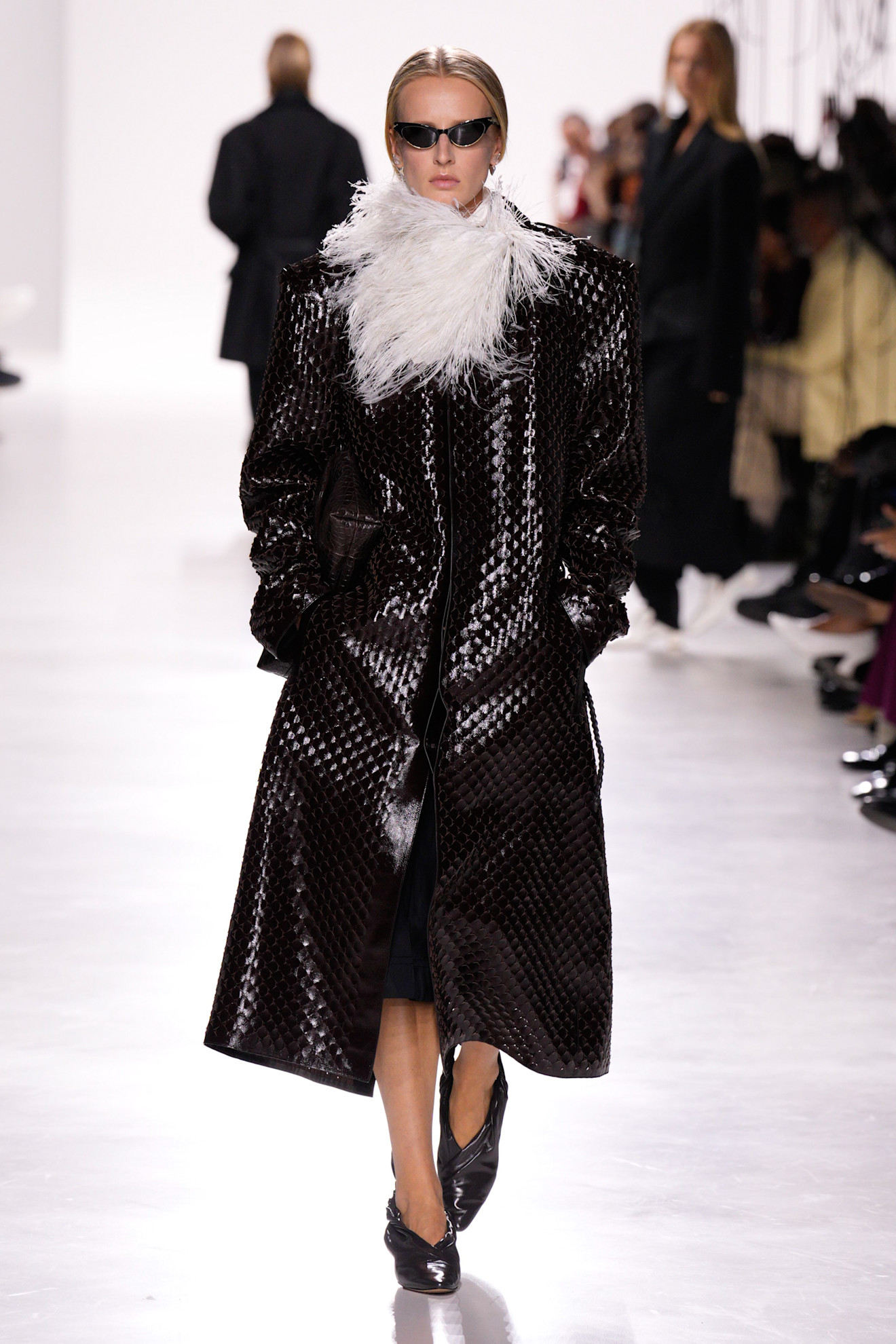 A model walking in the S/S 26 Bottega Veneta show wearing a brown Intrecciato coat.