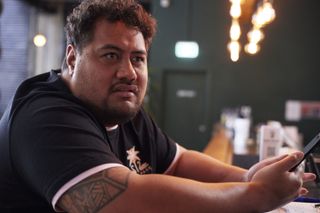 Brett (Michael Logo) sits at the bar of Echo Park Brewery with his phone in his hand, a look of disbelief on his face