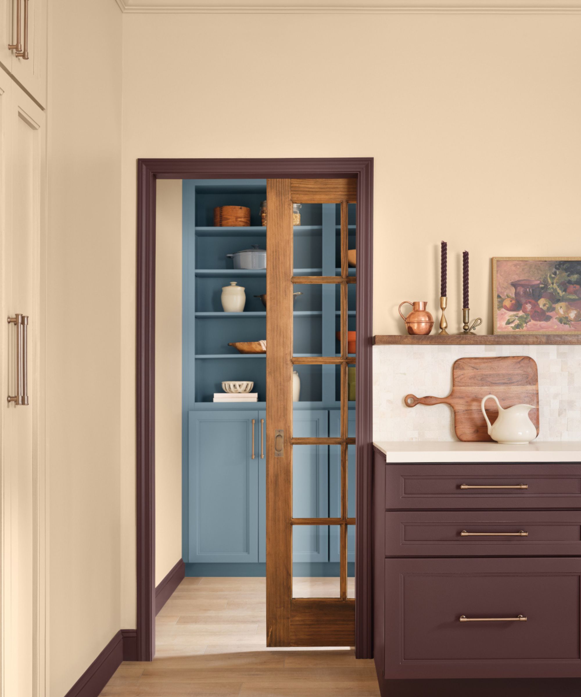 Kitchen with ivory walls, burgundy painted door frame, burgundy kitchen cabinetry and blue painted shelf cabinetry
