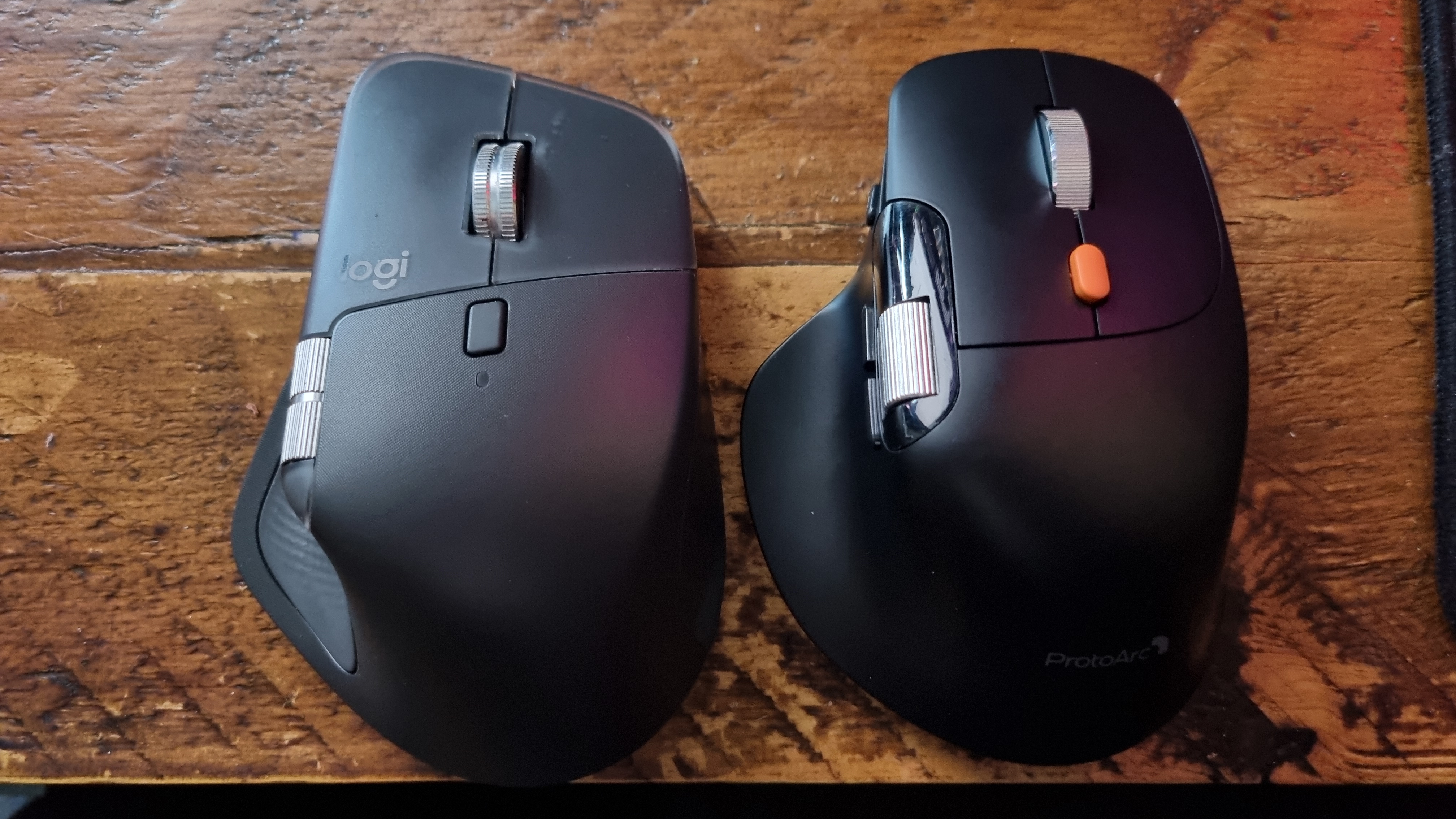 A Logitech MX Master 4 and a ProtoArc EM25 ergo mouse side by side on a desk