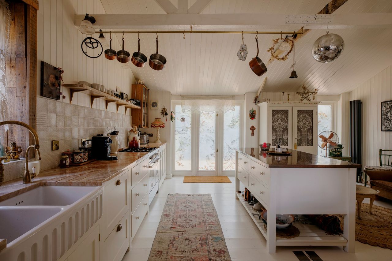 The kitchen surfaces are covered in brass and marble and it leads onto the garden decking through bifold doors