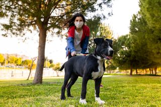 Person walking their dog while wearing a mask.