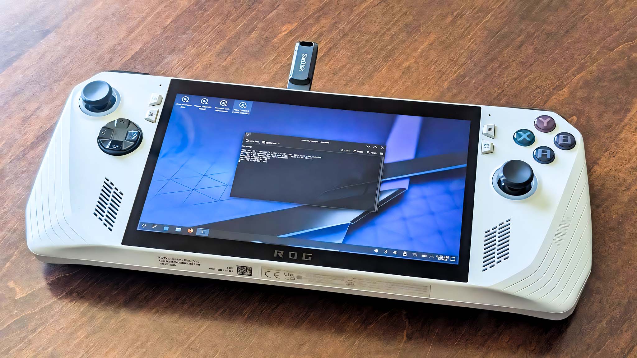 ROG Ally on a wooden table with a USB stick in its top port.