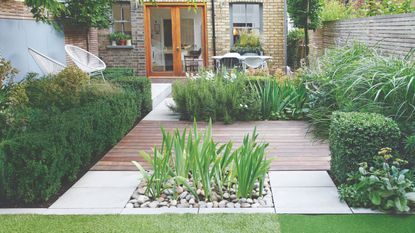 Garden decking and patio area surrounded by hedges and plants