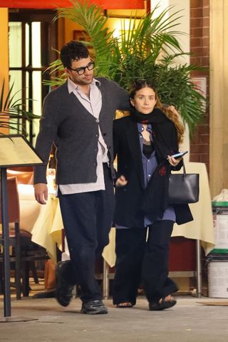 Ashley Olsen and Husband Louis Eisner walking in NYC wearing layered fall outfits including a blue button-down shirt and black lace-trim cami top