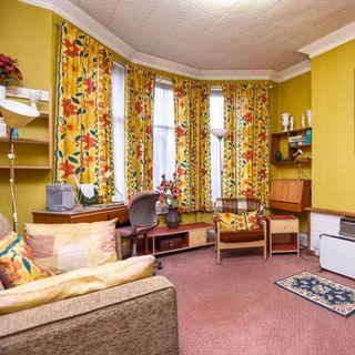 living room with yellow wall and floral curtains
