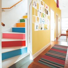 A staircase painted in a rainbow with a hallway wall painted in yellow