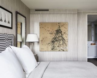 Neutral bedroom with artwork and ensuite beyond