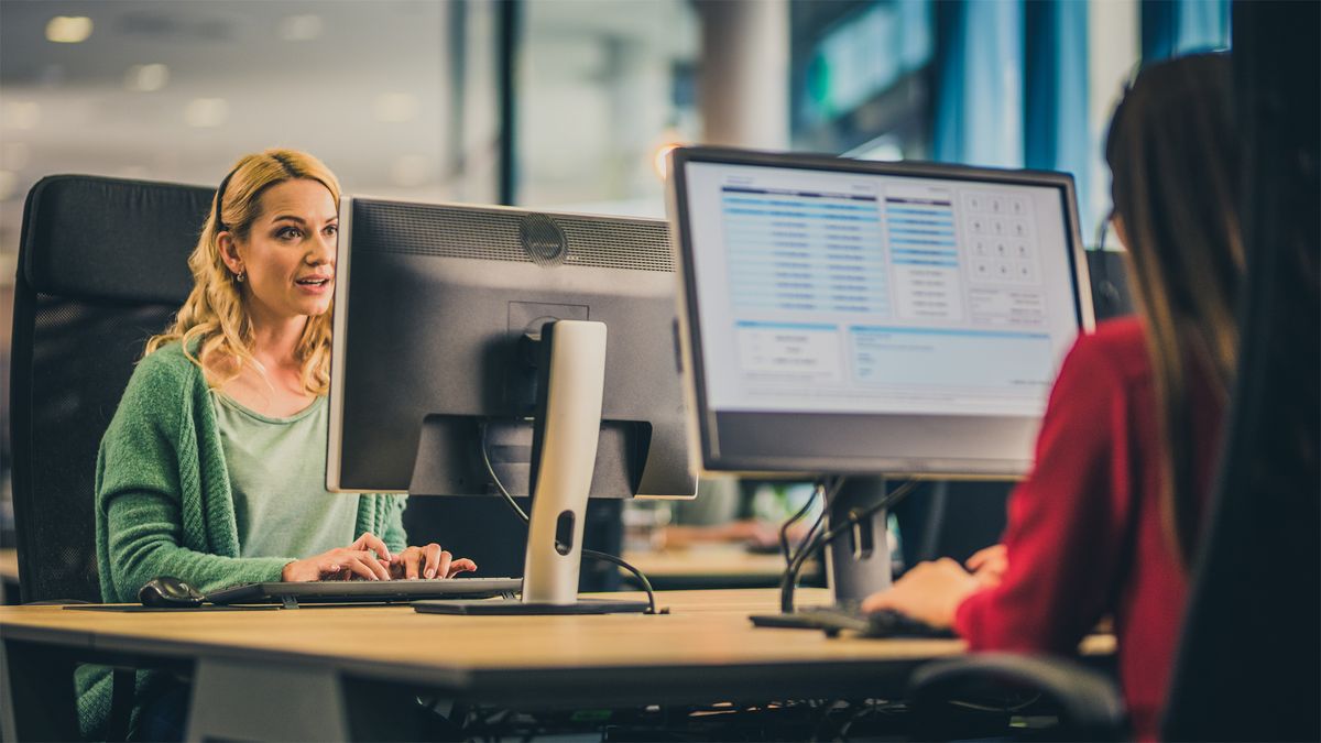 woman employed as IT support using a computer in an office while talking to a customer through a headset