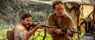 Daniel Bruhl and Jude Law pointing guns in Eden