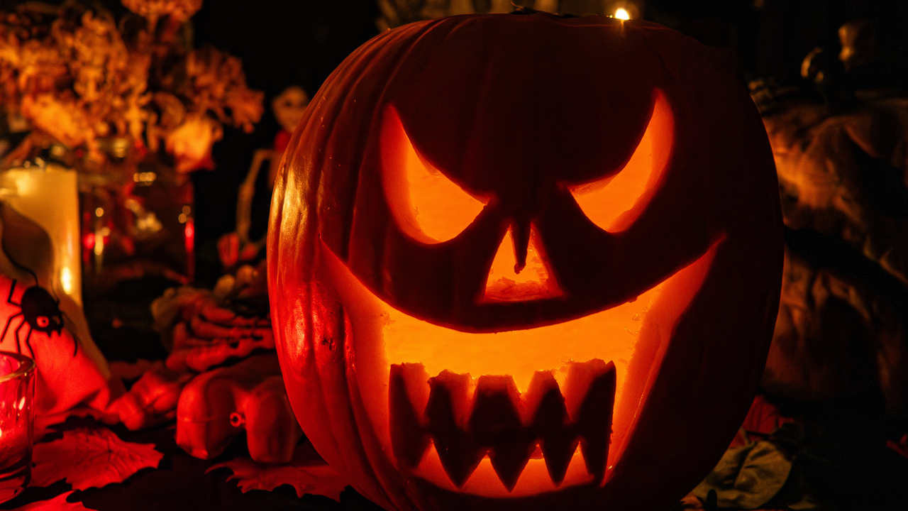 Carved pumpkin with scary face sits on table