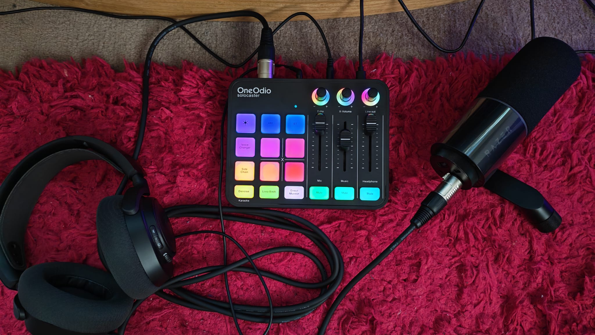 A OneOdio Solocaster sitting next to headphones and an XLR microphone