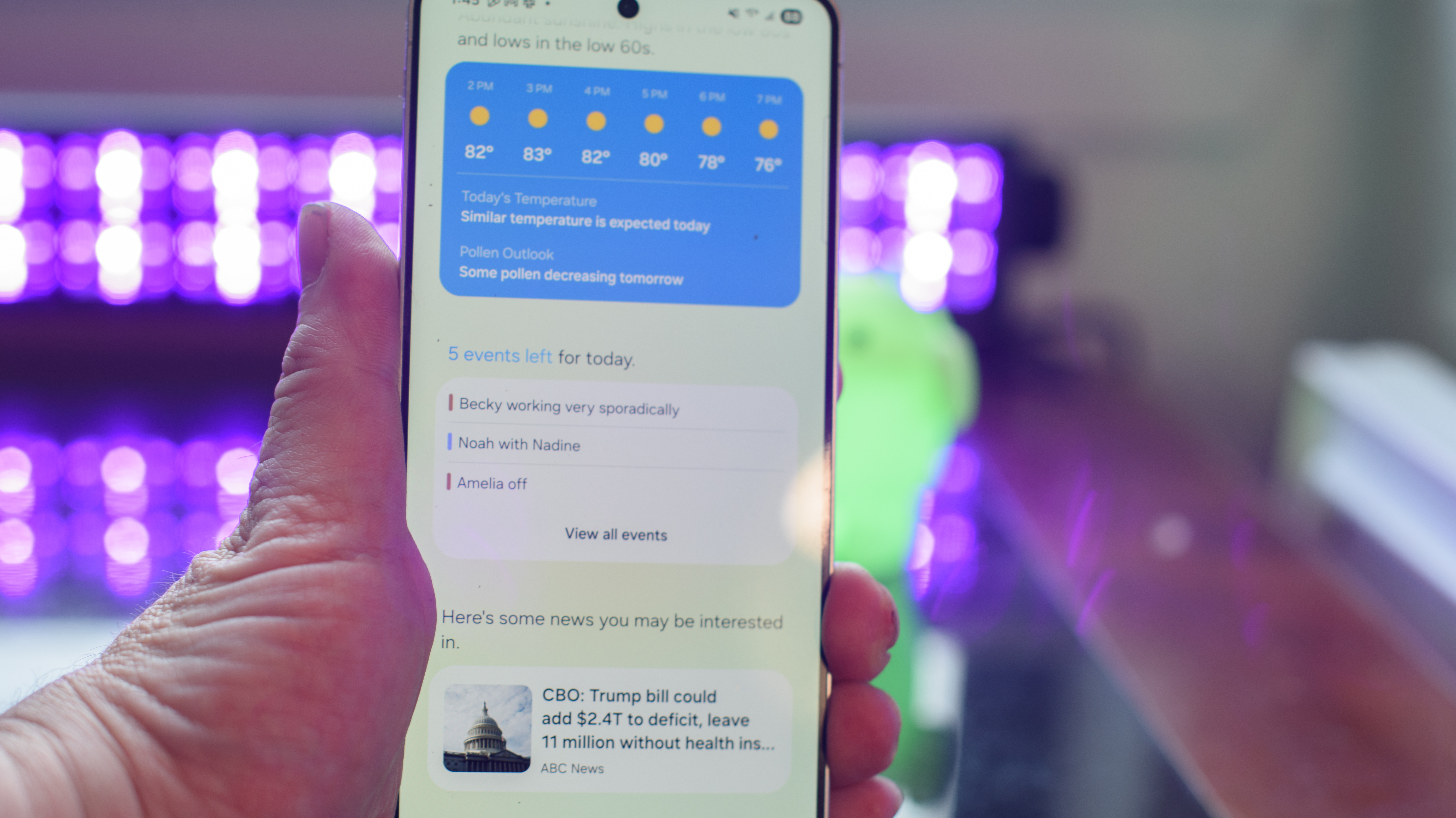 Samsung Galaxy S25 Edge showing the Now Brief app with black lights and an Android figuring blurred in the background