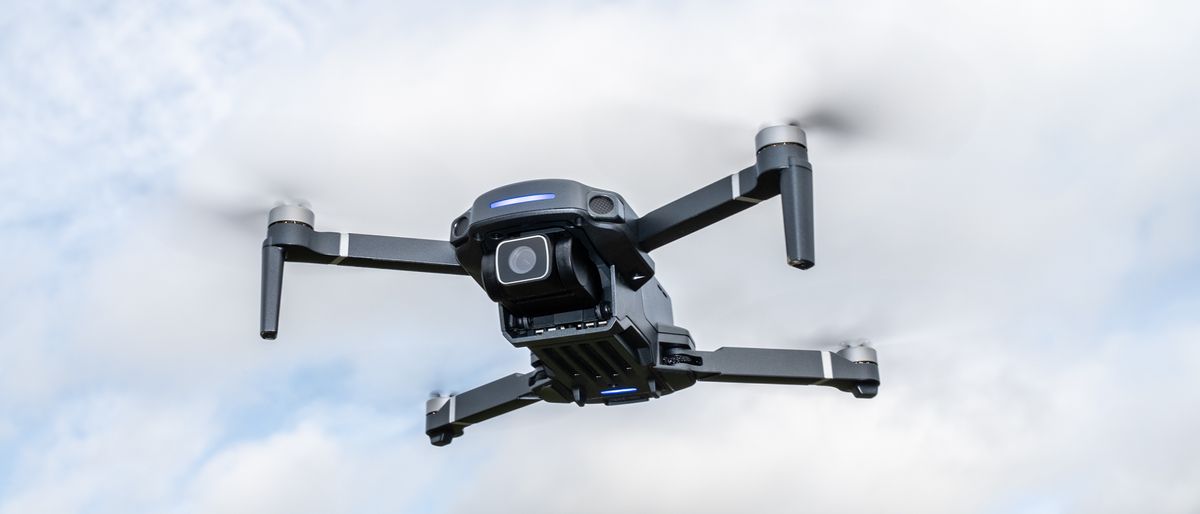 Holy Stone HS360S drone flying against a blue sky with white clouds