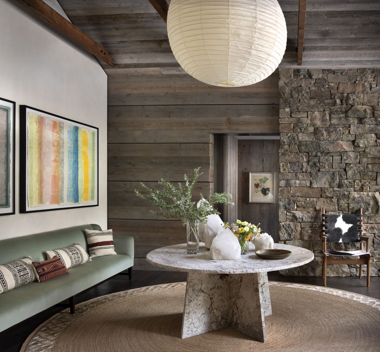 Entryway with table in center in front of bare brick wall and wall with bench and artwork.