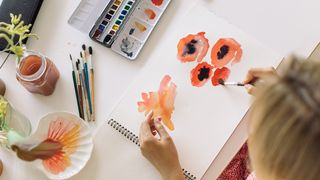 Best watercolour paints: a woman painting flowers with watercolours