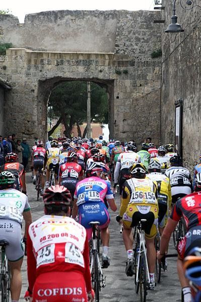 The peloton tries to fit through a hole in the wall.