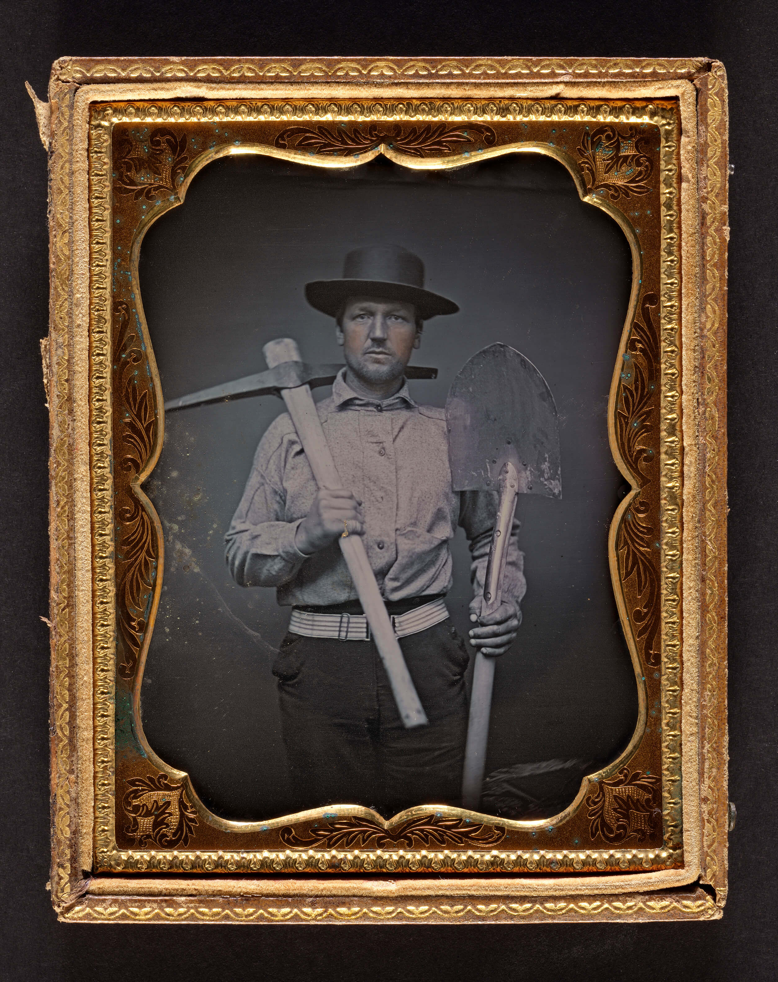 Old photo of man holding pick axe.