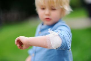 A young boy displaying his bandaged elbow.